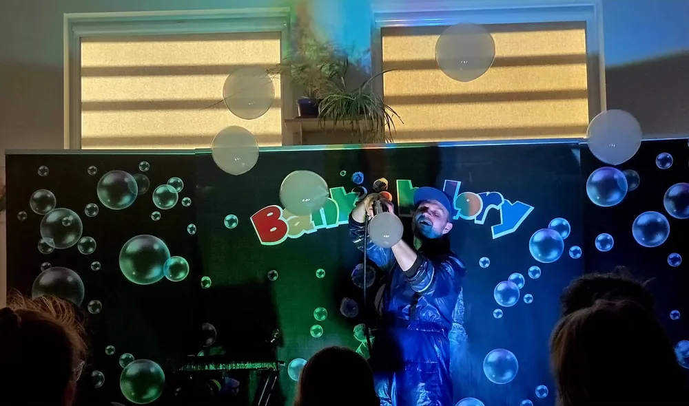 Pokaz baniek w świetle UV na scenie z logo Bańki i Kolory